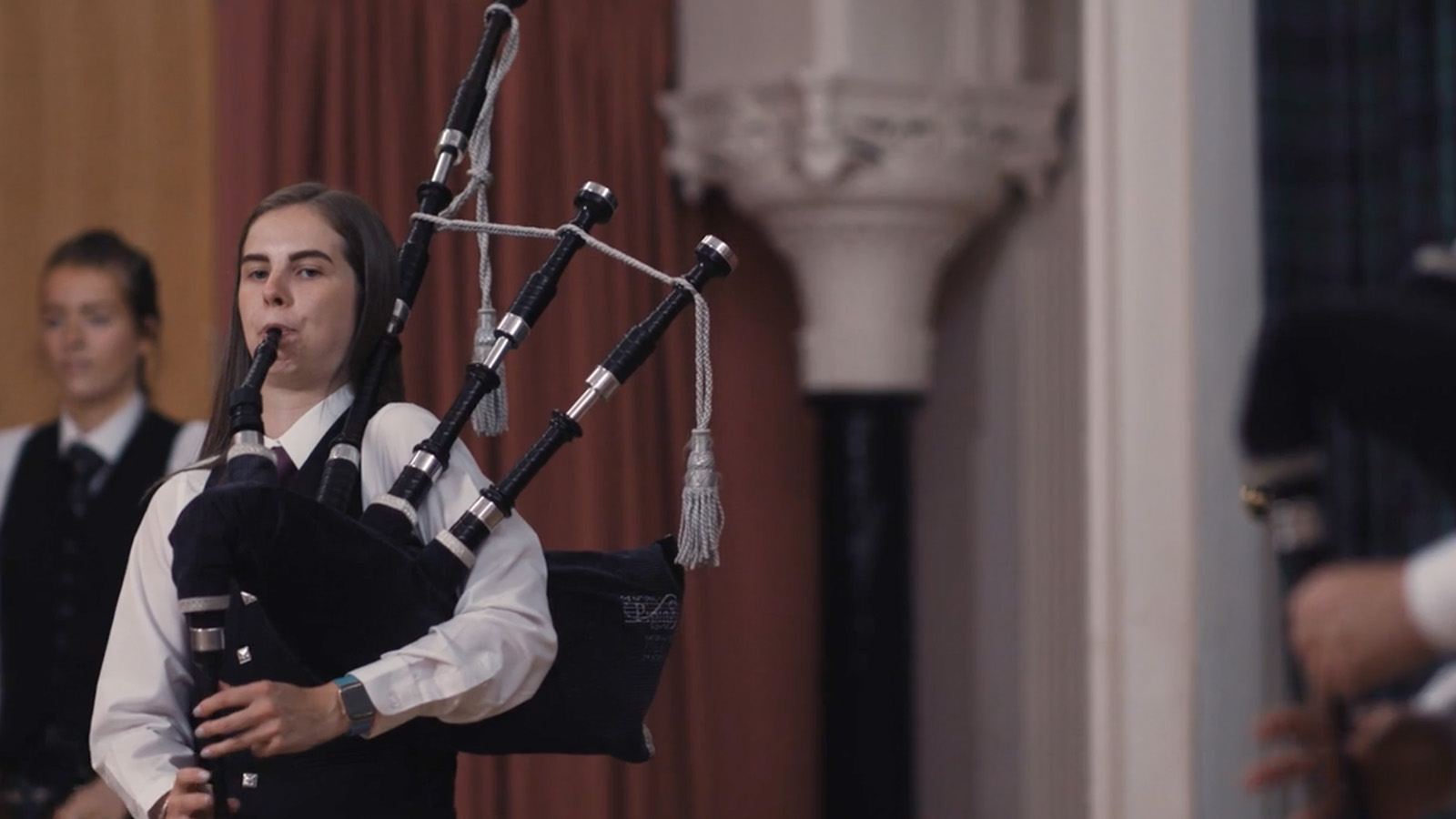 A young woman is pictured playing the bagpipes during a performance