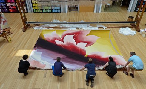 A group of people lay out a large print of a flower on a floor