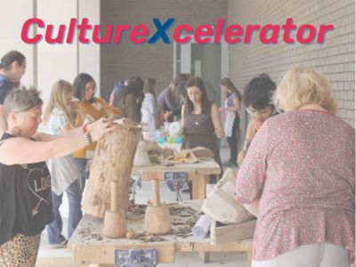 CultureXcelerator. A large bright room filled with people looking at items on tables.