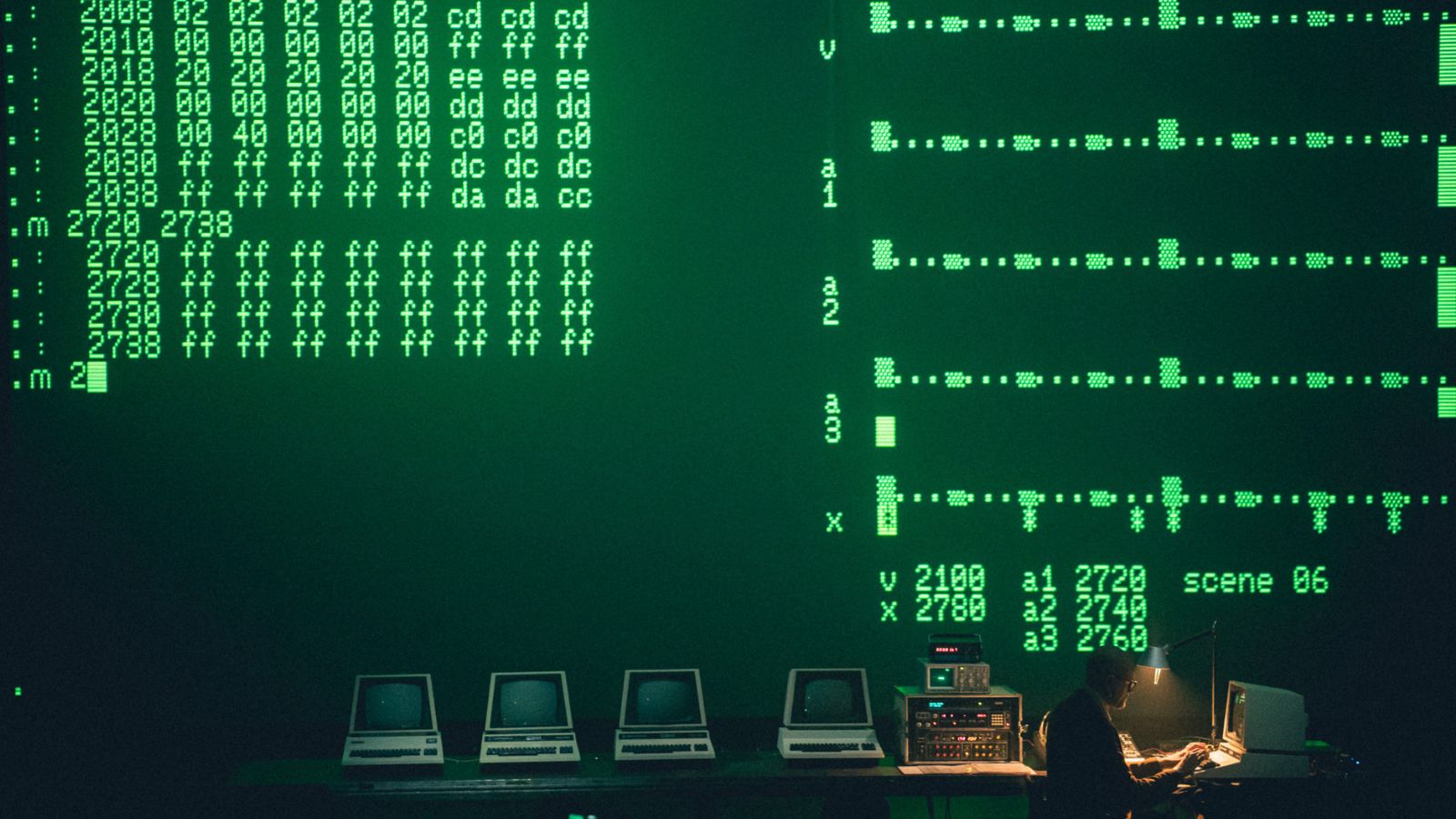 A screen is illuminated by green code on black as old computers become instruments