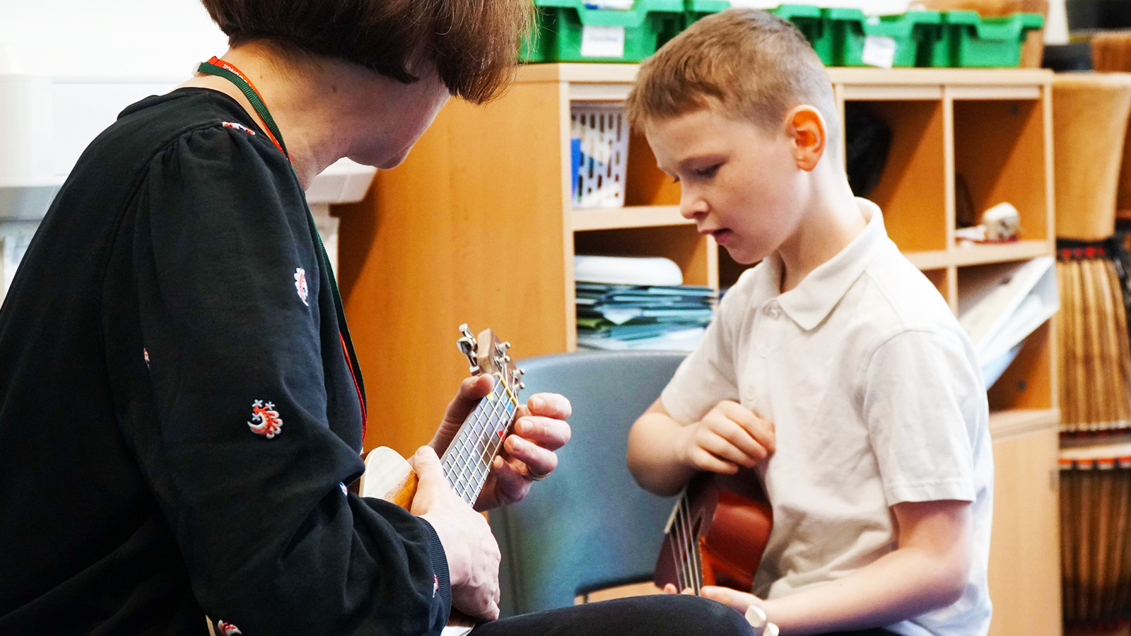YMI Tutor Julia Main plays the ukulele with a pupil at a YMI session at Murrayburn Primary