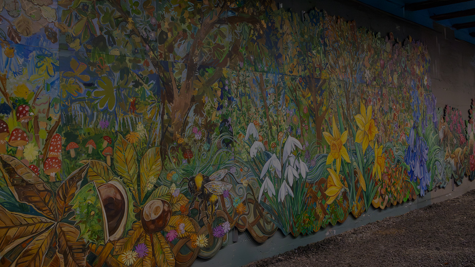 Alarge, bright, colourful, detailed mural of a woodland scene including wildflowers and trees.