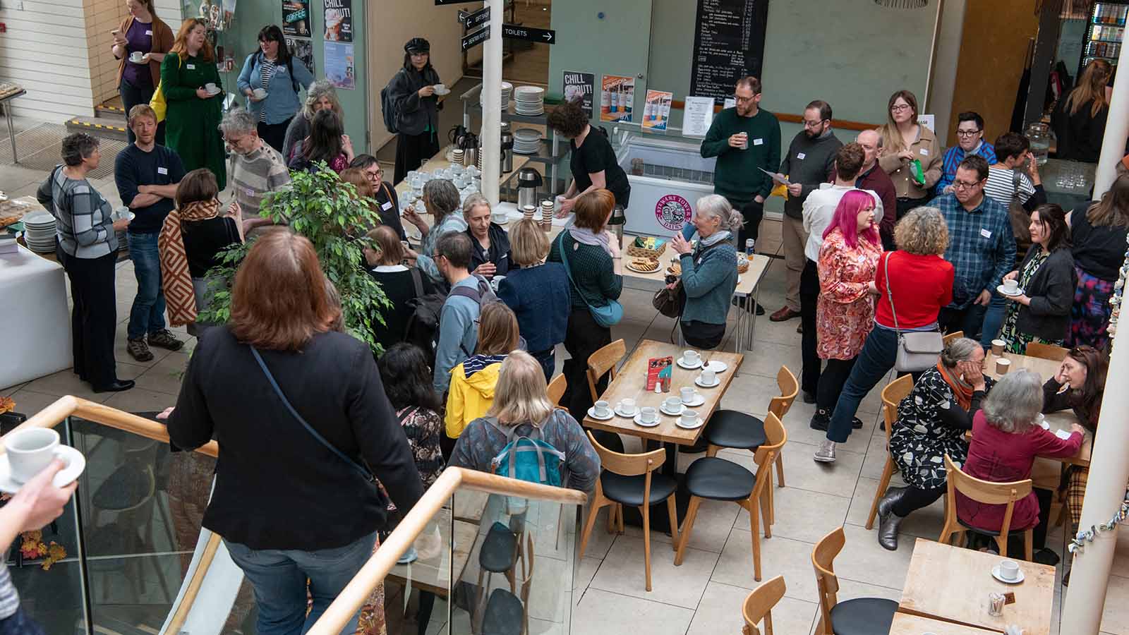 A mezzanine view above a crowd gathered together eating and drinking during a lunch break at the ICH conference