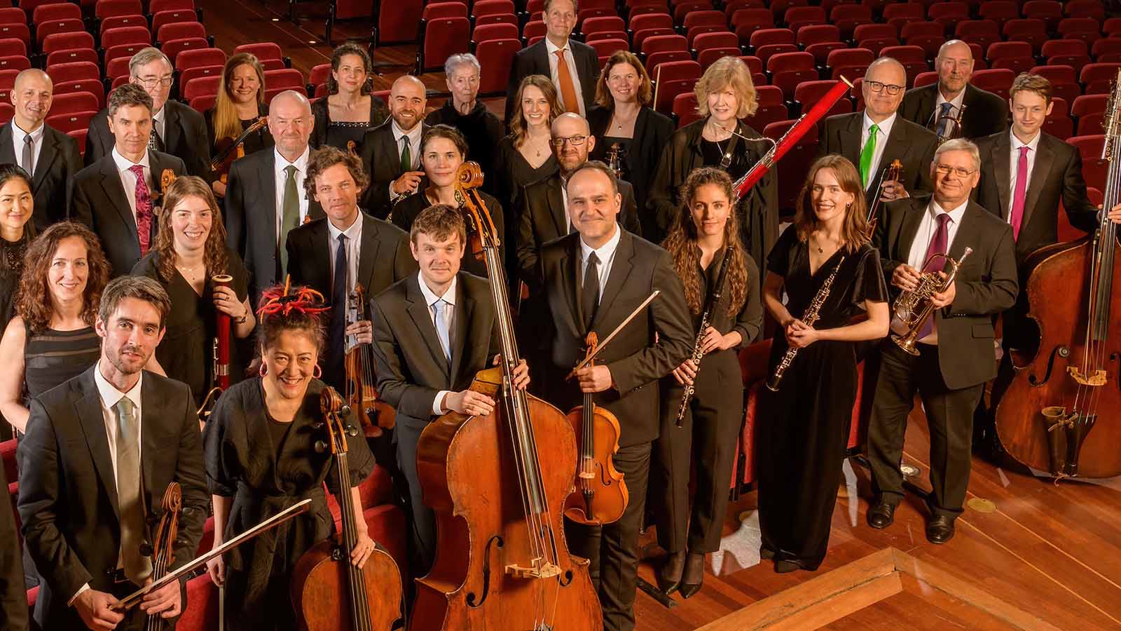 Members of the Scottish Chamber Orchestra pose with their instruments on the stage of a large auditorium.