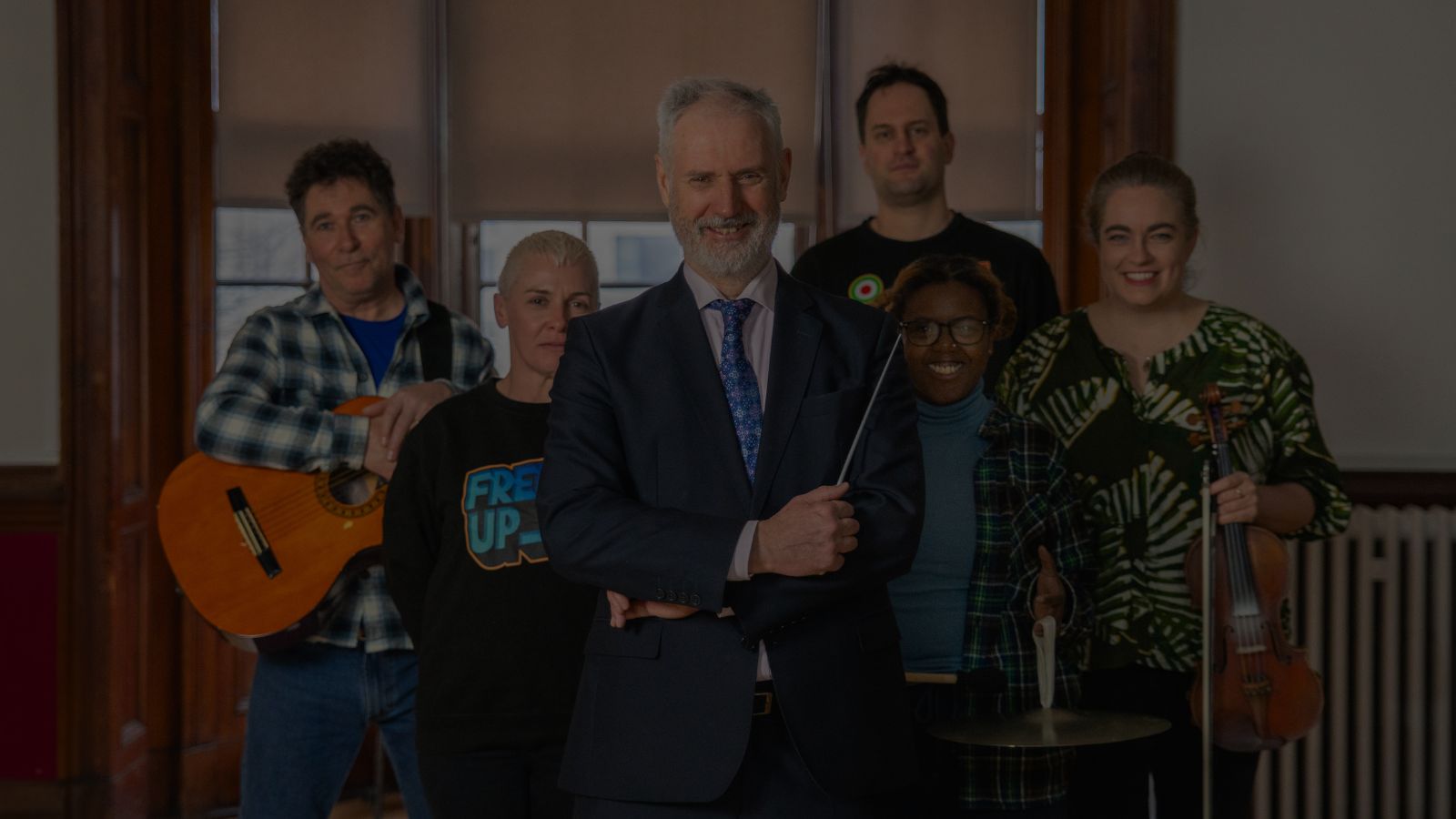 Musicians (Clark Innes, Louis Rive, Tina Freeland, Jerri Foreman) who will be playing at the Govan Music Festival, some holding a guitar and a violin, alongside Director of the Glasgow Barons Paul MacAlindin in the centre, holding a conductor’s baton, and Donna Boyd, Events Coordinator for FREED UP.