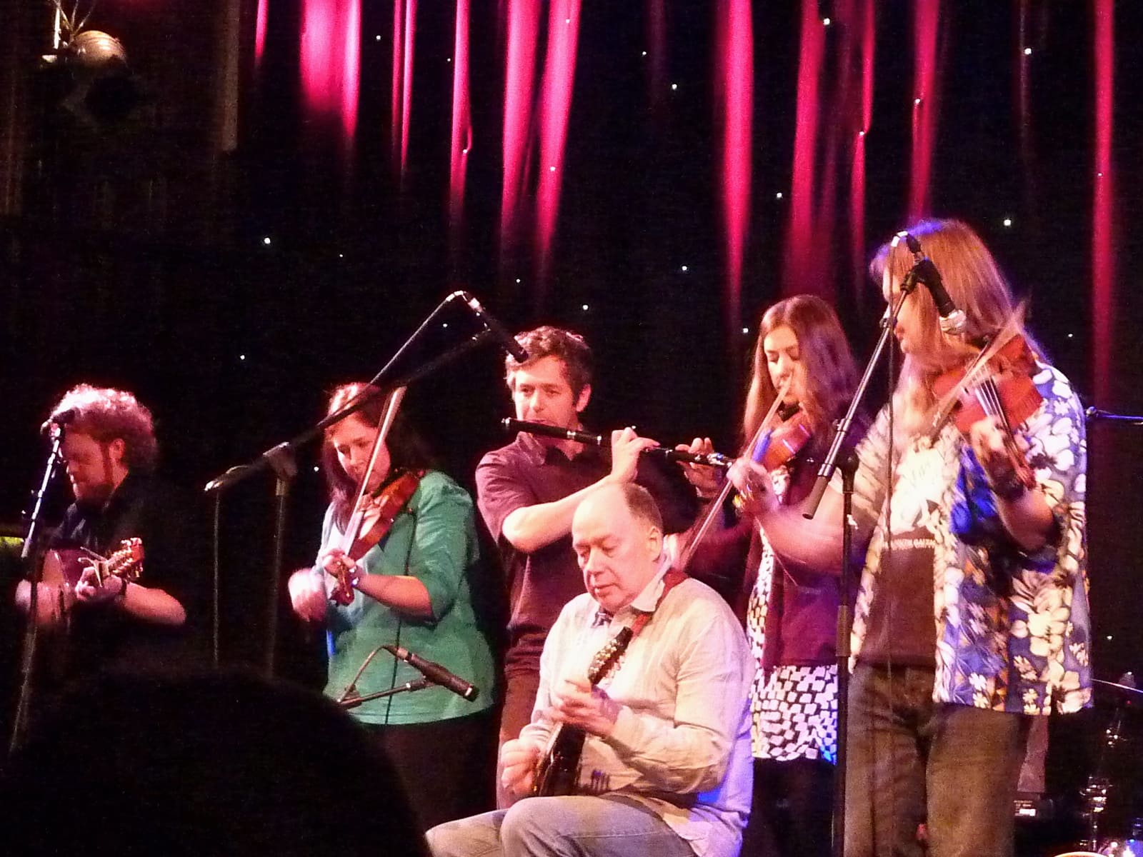 A group of musicians play fiddles on stage